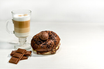 Glass of macchiato latte with dark chocolate and chocolate-filled donut.