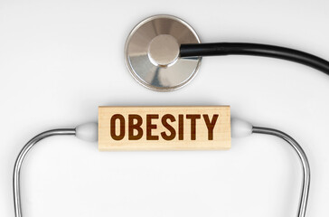 On the table is a stethoscope and a wooden plate with the inscription - Obesity