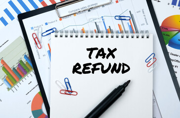 On the table are reports, charts, a notebook with the inscription - TAX REFUND