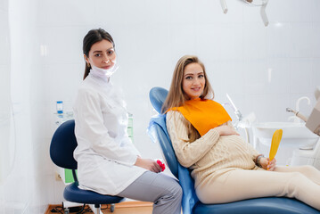 A professional dentist treats and examines the oral cavity of a pregnant girl in a modern dental office. Dentistry