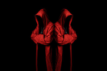 Mystery cult members in a red hooded cloaks in the dark. Unrecognizable person. Hiding face in...
