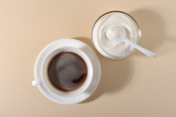 Collagen powder and cup of coffee on beige background.