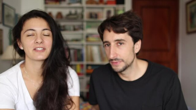 Modern millennial couple speaking to camera in video call