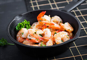Fried prawns. Roasted shrimps in skillet with lemon, parsley and garlic.