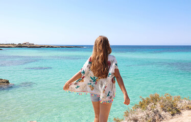 Summer holiday travel vacation concept. Back view girl dancing on Sicily beach.
