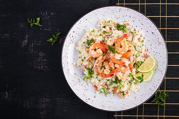 Couscous with roasted shrimps, tomatoes, red onions, almond nuts and parsley. Moroccan food with couscous and prawns. Top view, flat lay