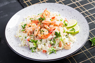 Couscous with roasted shrimps, tomatoes, red onions, almond nuts and parsley. Moroccan food with couscous and prawns.
