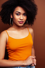 Fototapeta premium pretty young african american woman with curly hair posing cheerful gesturing on brown background, lifestyle people concept