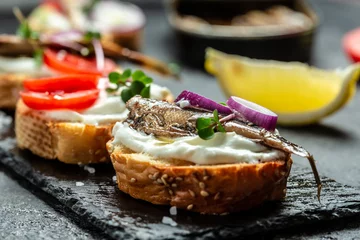 Foto op Aluminium Sandwiches with sprats on toasted bread with fish, fresh tomatoes and onion. Food recipe background. Close up © Надія Коваль