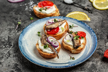 Sandwich with sprats and tomatoes on white plate. Danish cuisine. Food recipe background. Close up