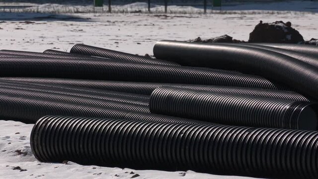 Corrugated double-walled pipes. Pipes for use in outdoor Sewerage systems. New black plastic sewer pipes are located outdoors. Construction site with pipes of different diameters.
