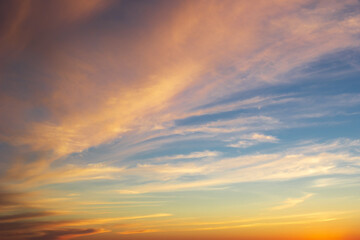 Dramatic majestic clouds on blue sky with yellow pink tones in sunset light, beautiful scenic cloudscape in sundown dusk