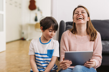 mother and son sitting at home and using digital tablet