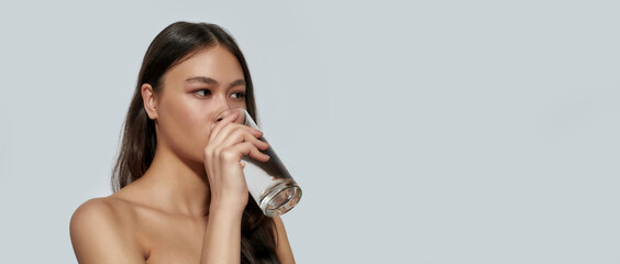 Pretty young asian girl drinking water from glass - obrazy, fototapety, plakaty