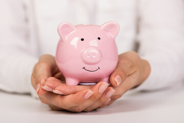 Piggy bank in hand on light  background, space for text. Finance, saving money. Business to success and saving for retirement concept
