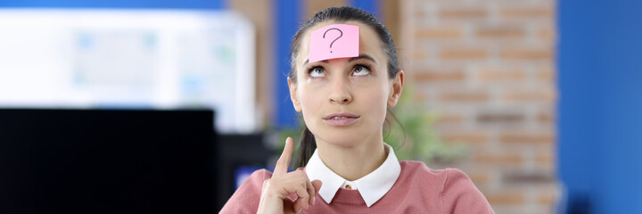 Pink sticker with question mark gluing to womans forehead