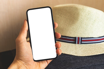 Travel mockup concept, man hand hold smartphone with blank white screen on background of straw hat, copy space photo