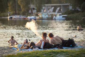 people enjoying sunset on a lake beach 