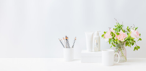 Home interior with decor elements. Pink tulips in a vase on a light background, cosmetic set