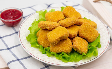 Chicken nuggets on a plate with lettuce leaves. Served on a napkin.