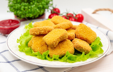 Chicken nuggets on a plate with lettuce leaves. Served on a napkin.