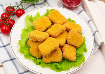 Chicken nuggets on a plate with lettuce leaves. Served on a napkin.