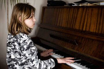 At home, a young girl plays the piano and looks away, she checks herself or knows a piece of music...