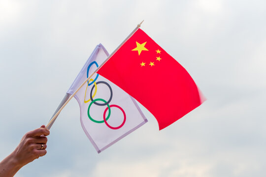 Fan waving the national flag of .China and the Olympic flag with symbol olympics rings.