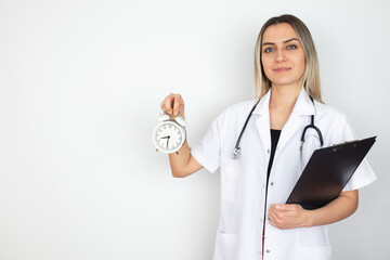 Portrait of a female doctor smiling and holding clock. isolated in white background
