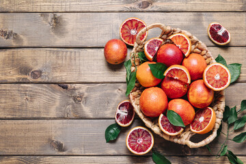 Pile of blood oranges in a basket on a wooden table background. Flat lay, top view, copy space