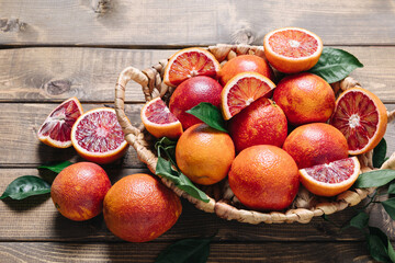 Pile of blood oranges in a basket on a wooden table background. Copy space