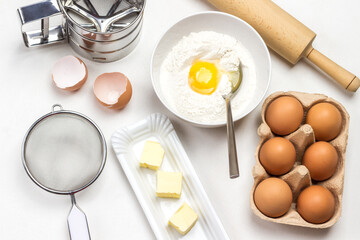 Brown chicken eggs in carton container. Flour, broken egg and spoon in bowl
