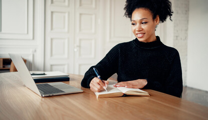 A woman of African-American appearance is a smart student getting an education via video link. Online distance learning communicates with the teacher. Works on a laptop computer.