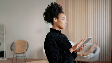 A freelancer prints text on a gadget. In his hands, he holds a tablet with statistics about the new...