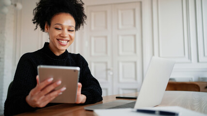 Remote communication with friends. Online training is watching videos on a computer gadget. Happy female student freelancer Latin American laughs working in a coworking space.