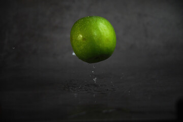 Fototapeta na wymiar floating in the air green apple dark background