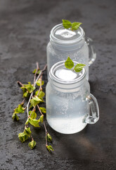 Russian traditional drink, natural fresh birch juice in a glass jar on a dark gray background