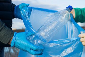 volunteers collect plastic bottles in bags, close-up of hands, the concept of ecology and protection of the earth