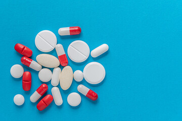  medical background of various tablets, pills, and capsules on a blue surface, top view, copy space, medicine, health, treatment, pharmacy concept
