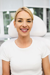 Portrait of beautiful young female patient sitting in medical chair and preparing for medical and beauty treatment with botulinum toxin injections.