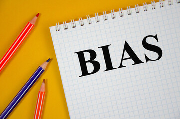 Handwriting text Bias word written on white notepad and yellow background