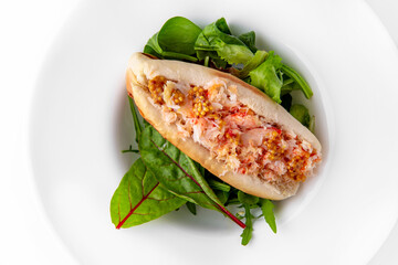 Hot dog with crab meat, mustard and herbs. Banquet festive dishes. Gourmet restaurant menu. White background.