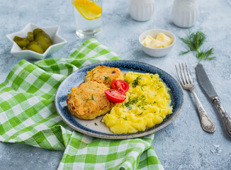 Homemade fish cakes or cutlets with mashed potatoes on a blue plate on a light concrete background. Fish recipes.