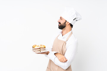 Young man holding muffin cake over isolated white background in lateral position