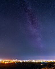 Milky way and stars in the sky above city lights. Night astrophotography