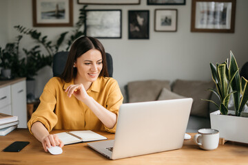 Head shot pleasant happy young woman freelancer working on computer at home. Attractive businesswoman studying online, using laptop software, web surfing information or shopping in internet store.