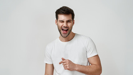 Happy bearded young man in white t-shirt winking
