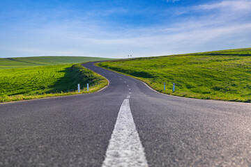 Asphalt road passing through green fields