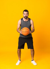 Fototapeta na wymiar Full-length shot of man over isolated yellow background playing basketball