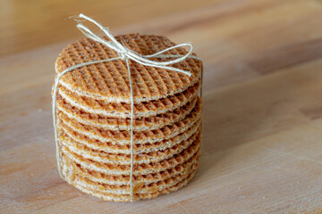 Stroopwafel on the wooden table with white background, Dutch waffle made from two thin layers of baked dough with a caramel syrup filling in the middle, Stroopwafels are popular in the Netherlands.